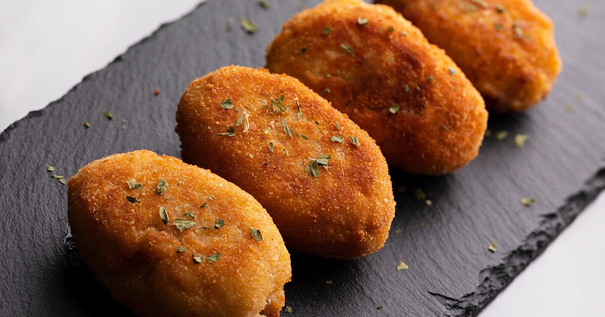 Croquetas on a black slate charcuterie board.